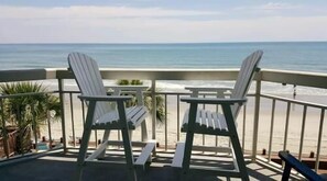 Two Adirondack chairs on a balcony overlooking a beach with a railing. - Water's Edge Resort #210 - Oceanfront in Garden City Beach, SC (Garden City)