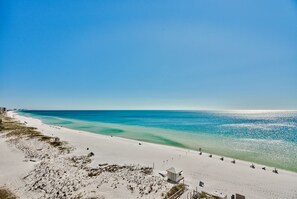 A beach with a sandy shore, a small building, and a clear blue sky. - Gulf Front, Renovated unit in Pelican Beach Resort, Wi-Fi, Cable (Destin)