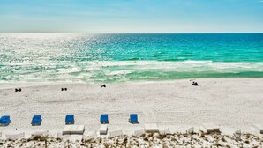 A beach with white sand, a few blue lounge chairs, and a clear view of the ocean. - Gulf Front, Renovated unit in Pelican Beach Resort, Wi-Fi, Cable (Destin)