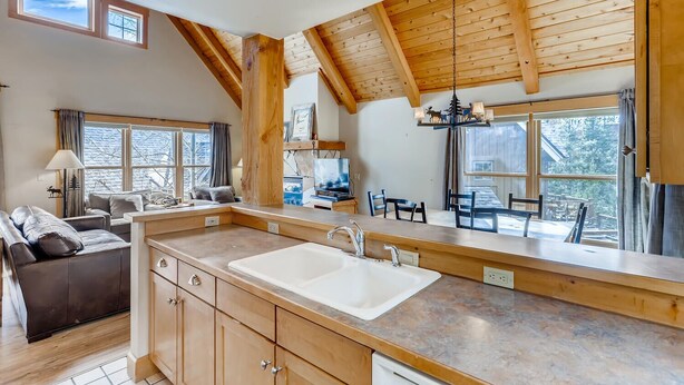A spacious kitchen with a large island, wooden beams, and large windows offering views of the outdoors. - Large, perfectly located Mountain Cabin, 3 bed + loft/3 bath (Dillon)