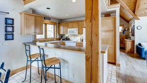 Una cocina amplia con armarios de madera, una isla grande con taburetes de bar y un letrero acogedor.