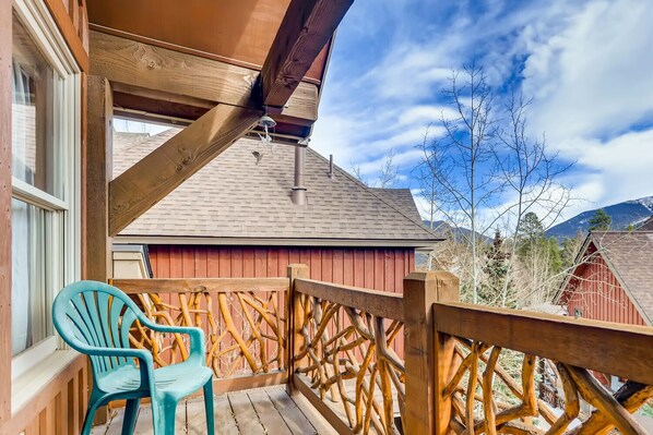 A wooden deck with a red building in the background, a clear sky, and a mountain range.