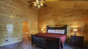 A wooden cabin bedroom with a bed, nightstands, and a ceiling fan. - Welcome to Black Bear Ridge (Gatlinburg)