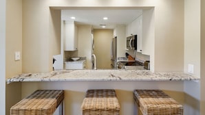 A modern kitchen with a marble countertop, stainless steel appliances, and a large mirror above the sink.