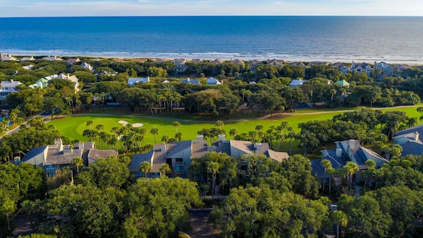 A coastal residential area with houses, a golf course, and a view of the ocean.