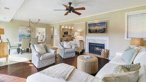 A spacious living room with a fireplace, a dining area, and a kitchen.