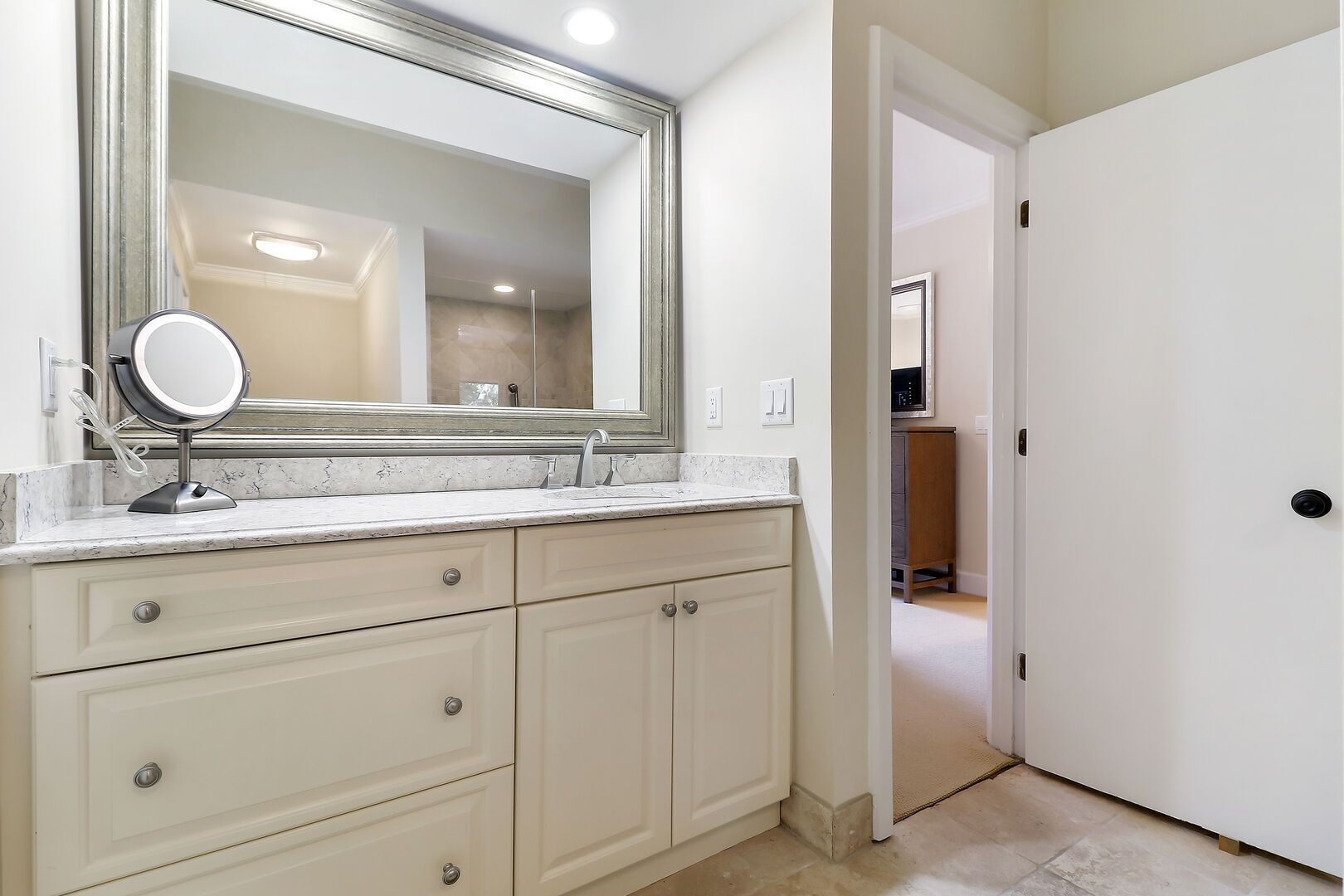 A bathroom with a large mirror, two sinks, and a walk-in closet.