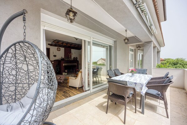 Patio esterno con mobili in vimini, un tavolo con tovaglia e una poltrona amaca.
