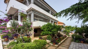A modern building with a covered outdoor area, potted plants, and a stone pathway.