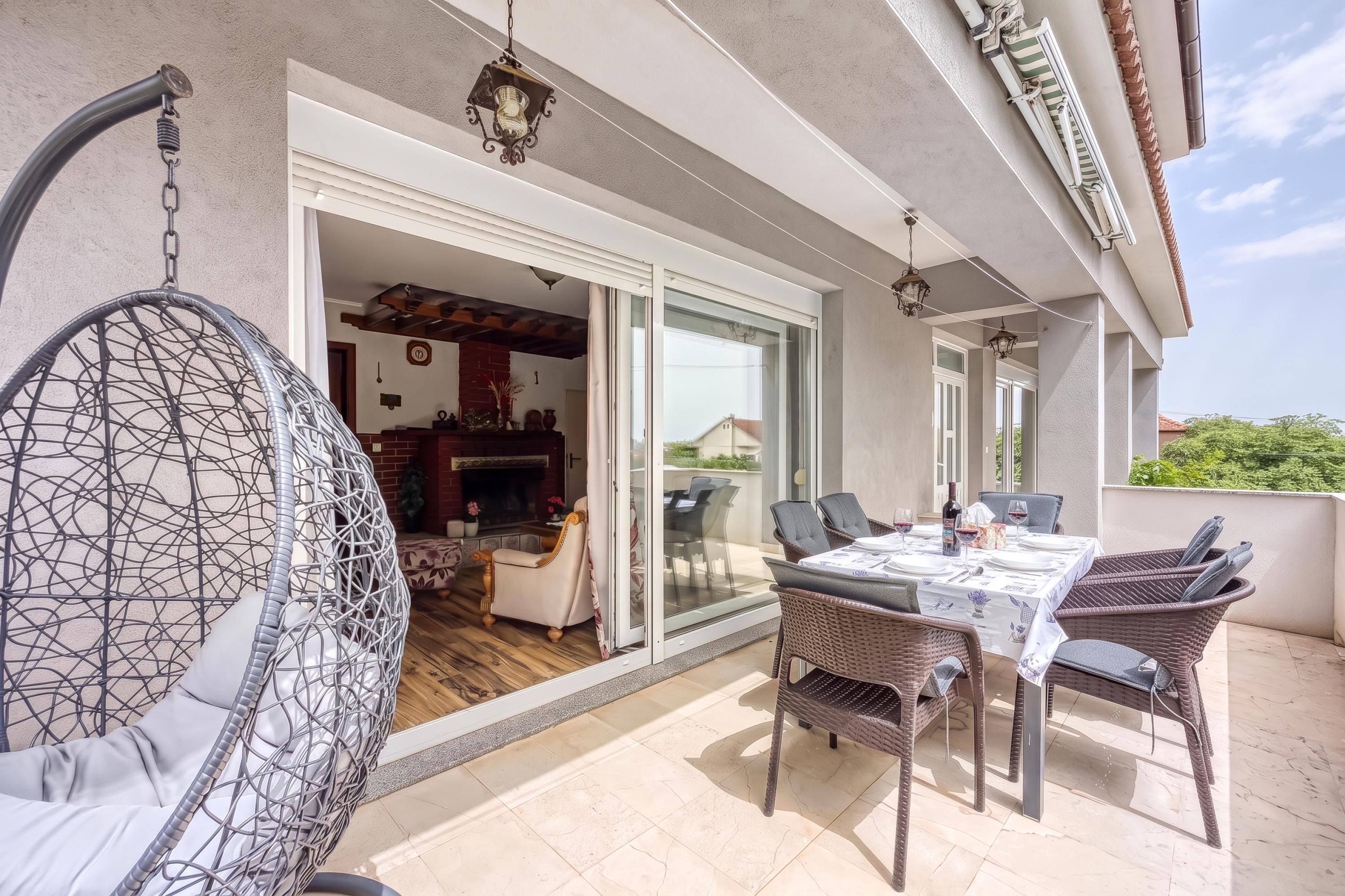 A patio with a dining table, chairs, and a hanging chair.