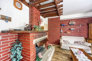 A living room with a brick fireplace, a white sofa, and a wooden coffee table. - Pool & Garden Apartment Bakija, Pakoštane, Croatia (Pakoštane)