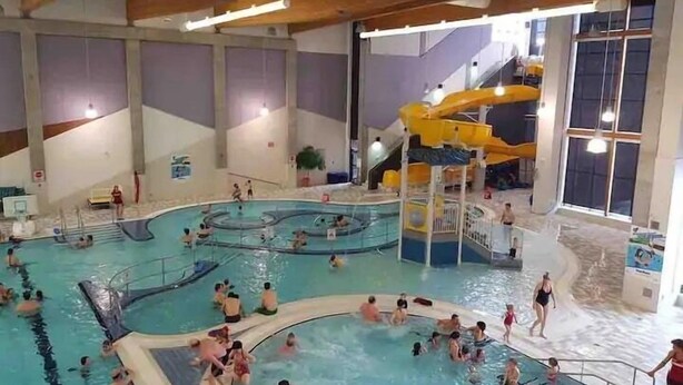 Een binnenzwembad met meerdere banen, een glijbaan en een speelgedeelte.