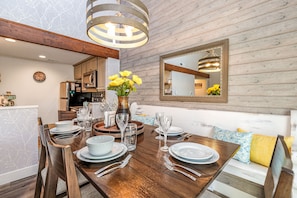 A dining area with a wooden table set for four, a vase with yellow flowers, and a mirror on the wall. - 2 Bedroom +Loft, 2 bath townhouse in The Galena Territory (Galena)