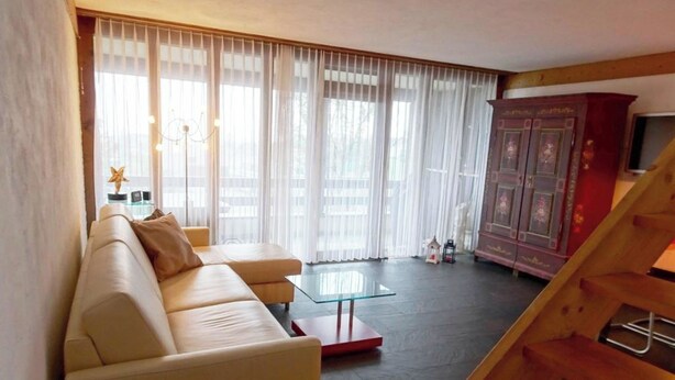 A living room with a sofa, a glass coffee table, a staircase, and a cabinet with a television. - Am Dürrbach 5/545 Appartement/Fewo 4-Bettwohnung by Interhome (Engelberg)