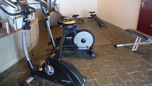 A gym with exercise equipment including an elliptical, a stationary bike, and a bench. - Am Dürrbach 5/545 Appartement/Fewo 4-Bettwohnung by Interhome (Engelberg)