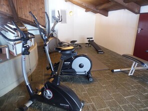 A gym with exercise equipment including an elliptical, a stationary bike, and a bench. - Am Dürrbach 5/545 Appartement/Fewo 4-Bettwohnung by Interhome (Engelberg)