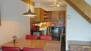 A modern kitchen with wooden cabinets, a dining table with red chairs, and a staircase leading to another level. - Am Dürrbach 5/545 Appartement/Fewo 4-Bettwohnung by Interhome (Engelberg)