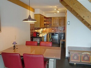 A modern kitchen with wooden cabinets, a dining table with red chairs, and a staircase leading to another level. - Am Dürrbach 5/545 Appartement/Fewo 4-Bettwohnung by Interhome (Engelberg)