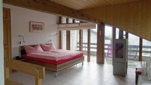 A bedroom with a bed, a television, and a large window. - Am Dürrbach 5/545 Appartement/Fewo 4-Bettwohnung by Interhome (Engelberg)