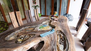 A dining table with a unique wooden design, surrounded by chairs. - MasBro ART Villas (Seminyak)