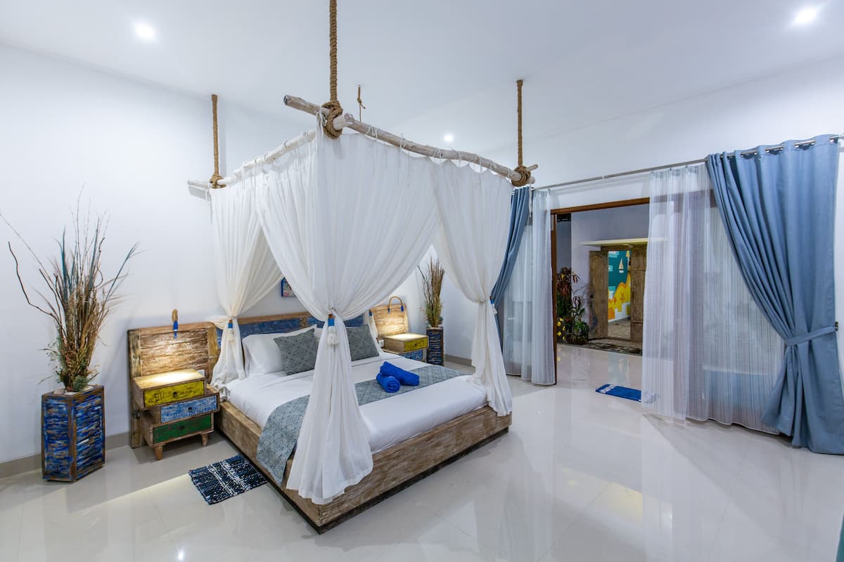 A modern bedroom with a wooden bed, white canopy, and blue curtains.