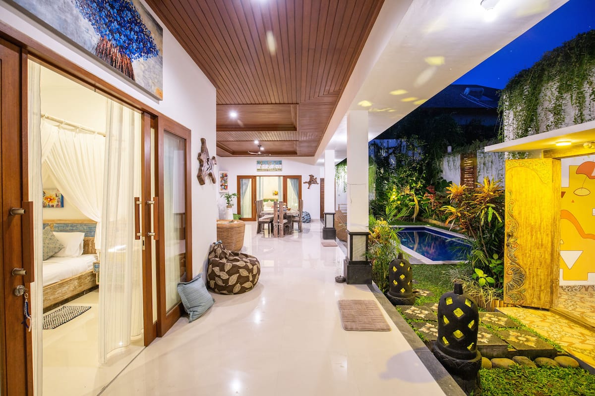 A corridor leading to a dining area with a view of a pool and garden.