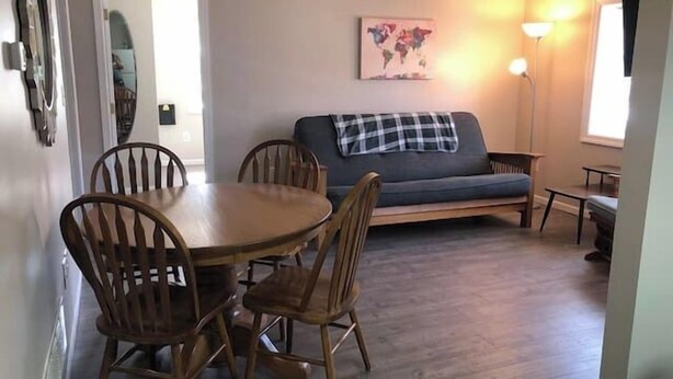 A dining area with a wooden table and chairs, a grey sofa, and a world map on the wall.