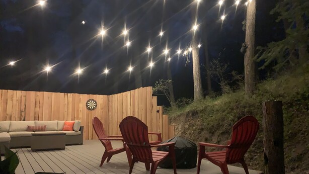 An outdoor deck with a wooden fence, a dartboard, and red chairs. - Secluded Peaceful Chalet 1 Bdrm King Suite AC, Private Laundry Room (Bigfork)