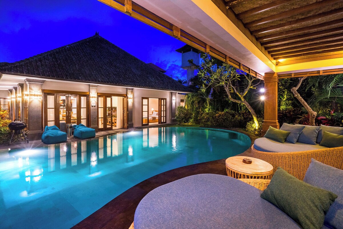 Ein Poolbereich mit Liegestuhl und kleinem runden Tisch, umgeben von einer Holzpergola.