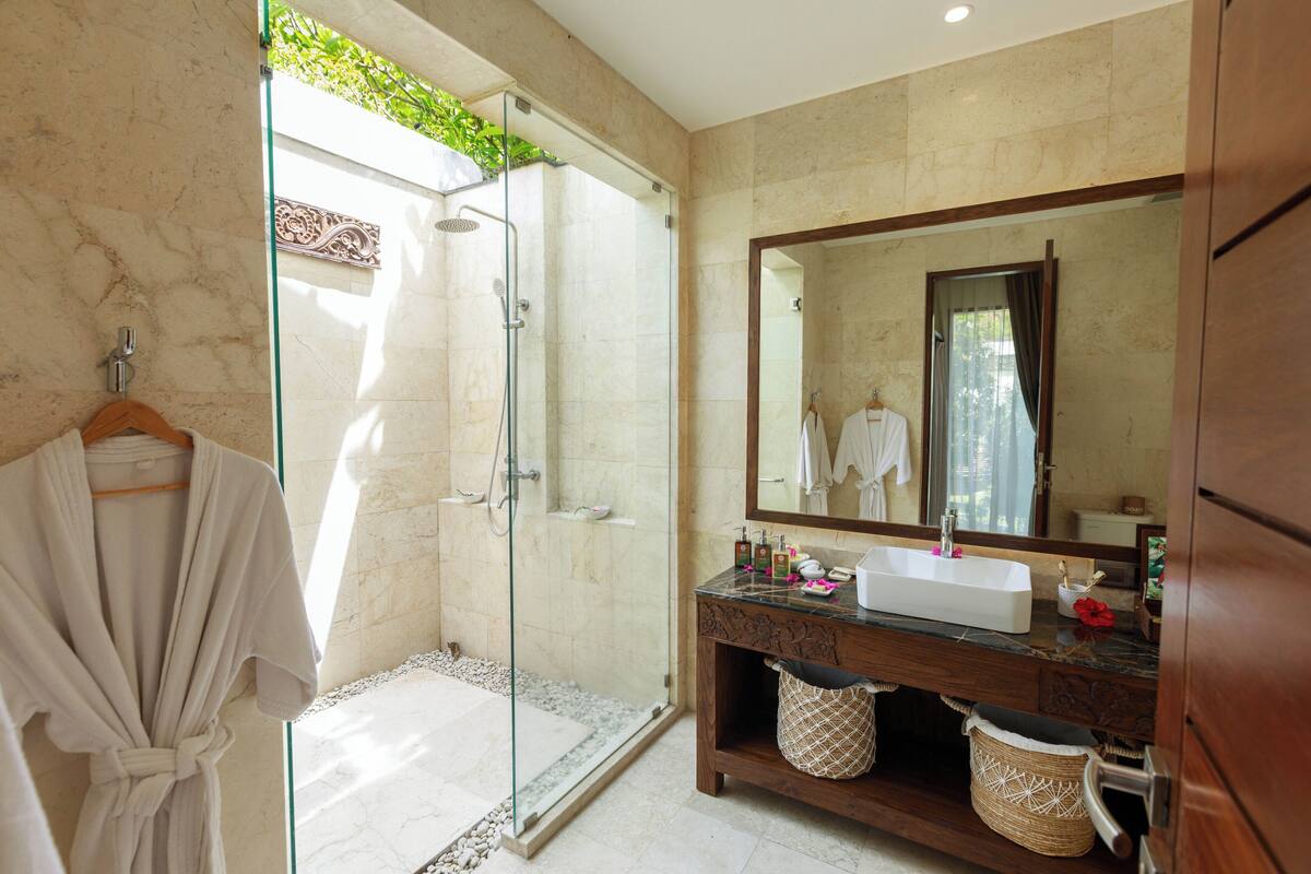 Une salle de bain dotée d’une douche à parois de verre, d’un meuble-lavabo en bois et d’un grand miroir.