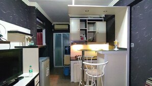 A compact kitchen with a refrigerator, a small dining area with two chairs, and a bar counter.