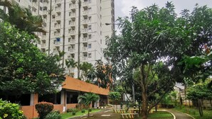 A residential area with a tall apartment building, a paved pathway, and greenery.
