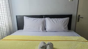 Una cama bien hecha con almohadas blancas y una colcha amarilla a rayas.