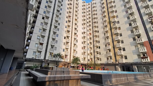 A high-rise residential building with multiple balconies, a central courtyard with seating, and a water feature.