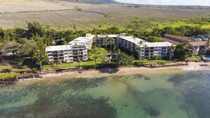 Ein Strandhotel mit mehreren Gebäuden, einem Sandstrand und klarem Meerwasser.