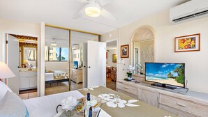 Ein Hotelzimmer mit Bett, Fernseher, Esstisch und Blick auf den Strand.