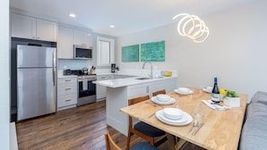 A modern kitchen with white cabinetry, a stainless steel refrigerator, and a wooden dining table set for four. - Modern Mid-Town Hideaway, Steps to Gondola, Walk Anywhere (Telluride)