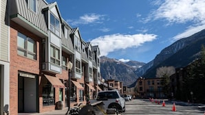 A street with buildings, a parked car, and mountains in the background. - Modern Mid-Town Hideaway, Steps to Gondola, Walk Anywhere (Telluride)