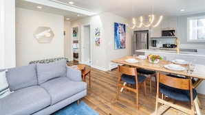 A modern living room with a gray sofa, wooden dining table, and chairs. There is a kitchen area with a microwave, stove, and cabinets. - Modern Mid-Town Hideaway, Steps to Gondola, Walk Anywhere (Telluride)