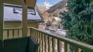 Ein Balkon mit Blick auf einen verschneiten Berg und ein Haus.