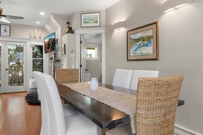 A dining area with a long table, wicker chairs, and a white vase.