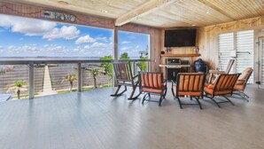A covered outdoor area with a view of the bay, wooden furniture, and a flat-screen TV.