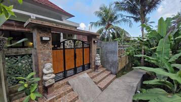 A house with a stone facade, a wooden gate, and a small statue.