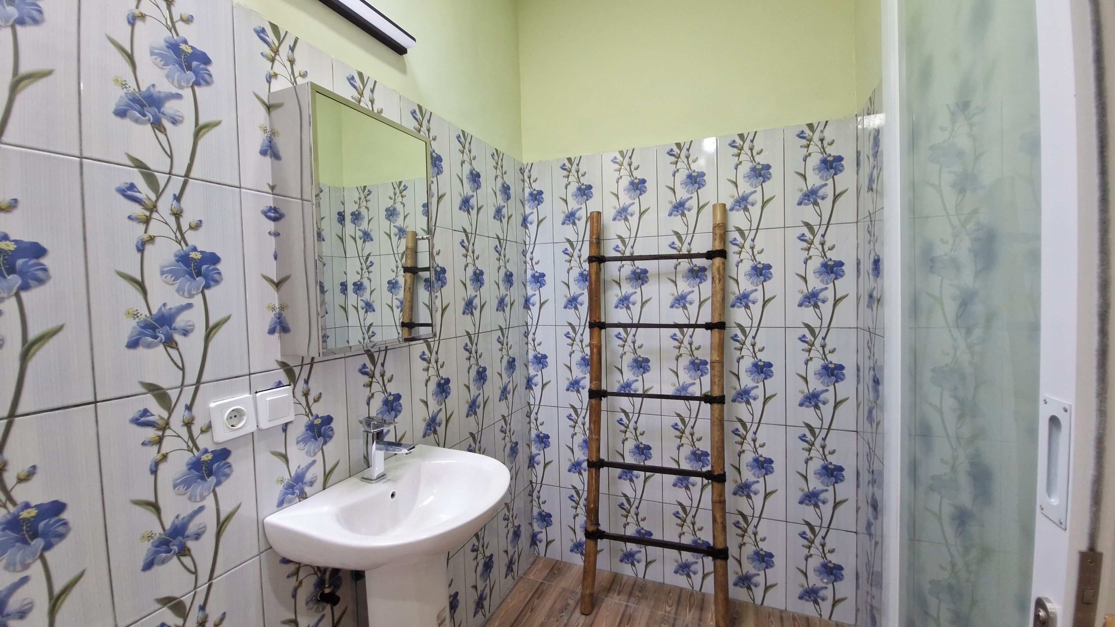 Un baño con lavamanos blanco, un espejo y zona de ducha.
