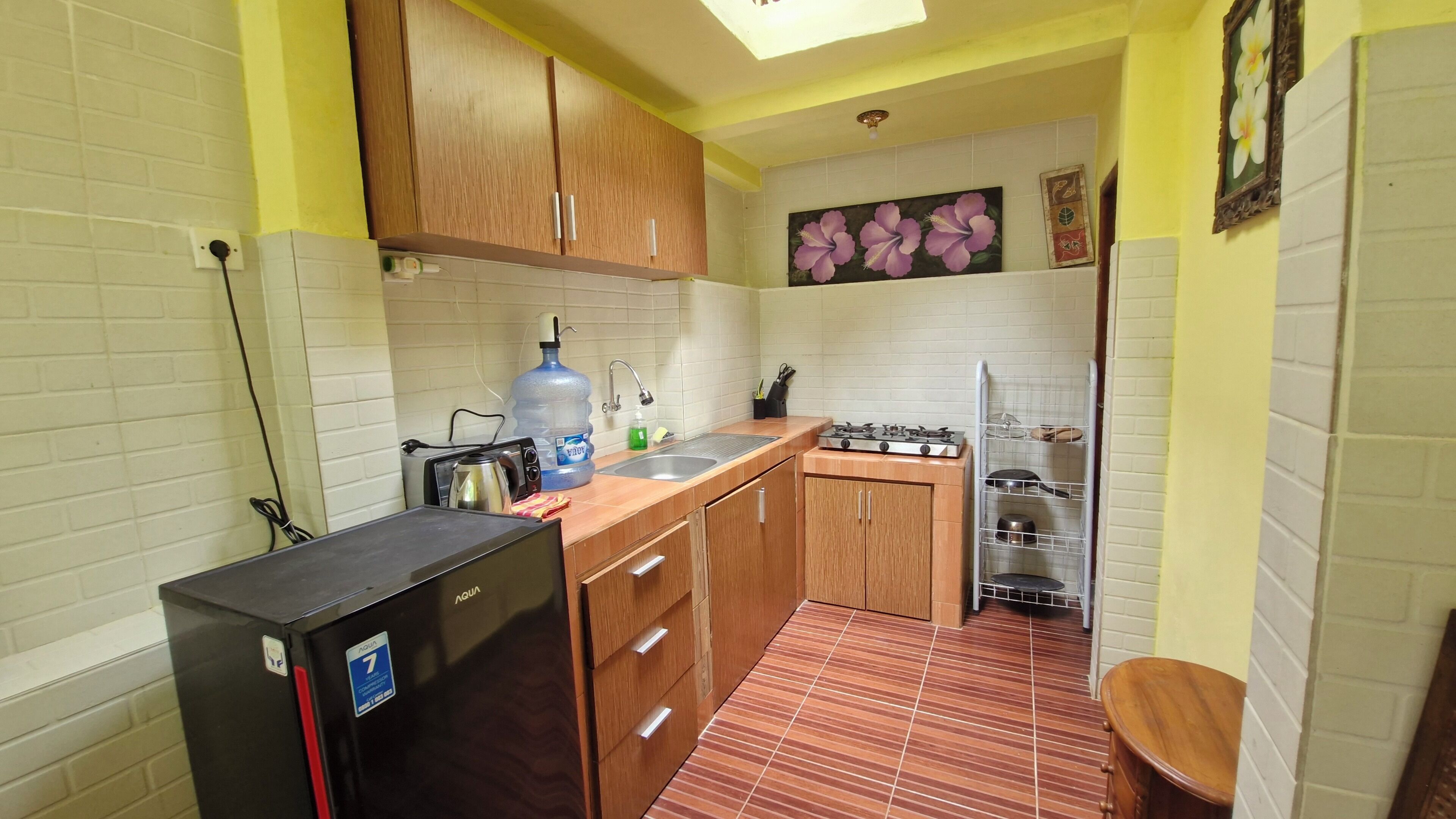 A compact kitchen with wooden cabinets, a gas stove, a sink, and a water dispenser.