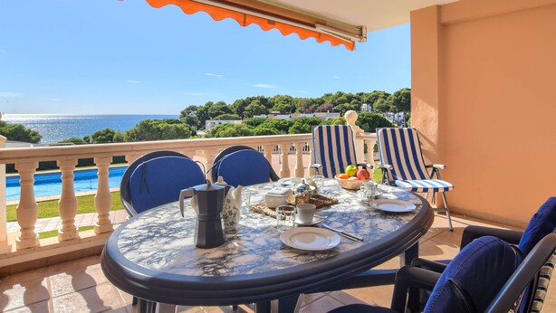 A balcony with a table set for two, chairs, and a view of the sea. - Poolbeach VI 4 pax - Moraira, Costa Blanca (Moraira)
