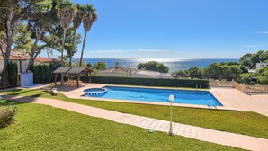 A swimming pool with a view of the sea, surrounded by a well-maintained lawn and a gazebo. - Poolbeach VI 4 pax - Moraira, Costa Blanca (Moraira)