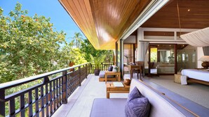A balcony with a wooden railing, a sofa, and a table with cushions. - Baan Kilee (Koh Samui)