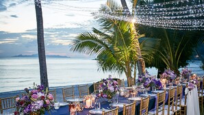 A long table set for a formal outdoor event with chairs, tablecloths, and floral centerpieces. - Baan Kilee (Koh Samui)