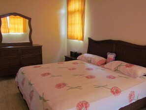 Un dormitorio con cama, cómoda, mesita de noche y espejo.